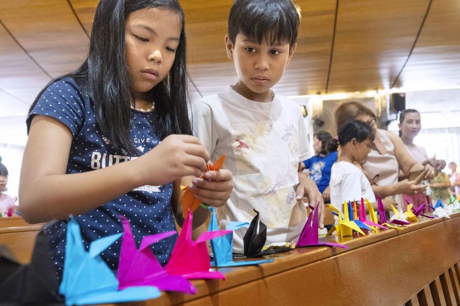 鶴を折る子どもたち＝４月２１日、フィリピンの首都マニラ近くのケソン市（共同）